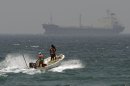 With an oil tanker in background, fishermen cross the sea waters off Fujairah, United Arab Emirates, Wednesday, May 30, 2012. The United Arab Emirates is nearing completion of a pipeline through the mountainous sheikdom of Fujairah that will allow it to reroute the bulk of its oil exports around the Strait of Hormuz at the mouth of the Gulf, the path for a fifth of the world's oil supply. (AP Photo/Kamran Jebreili)