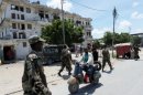 A Somali man rides his scooter past soldiers in Mogadishu