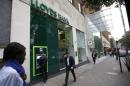 People walk past a branch of Lloyds Bank at Berkeley Square in London