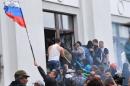 A man waves a Russian flag as pro-Russian activists break a window to enter the regional administration building in the eastern Ukraine city of Lugansk, on April 29, 2014