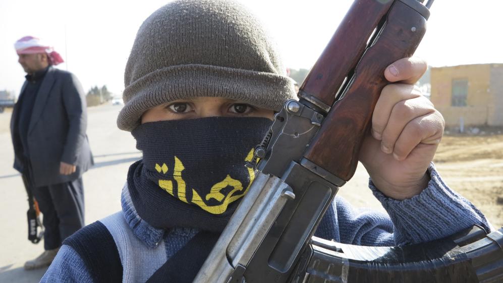 A boy holds his Kalashnikov rifle on the streets of the city of Ramadi