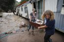 FILE - In this Sept. 13, 2013 file photo, water rushes through her destroyed home as resident Holly Robb, left, and her neighbor Pam Bowers salvage belongings after storms that raged through the Rocky Mountain foothills in this photo made in Lyons, Colo. Two low-lying trailer parks in the small town, 20 minutes to the north of Boulder, bore the brunt of the recent flooding. 