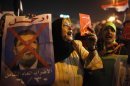 A protester holds a crossed out picture of President Mohamed Mursi while chanting anti-Mursi and anti-Muslim Brotherhood slogans as they wait in Tahrir square ahead of Mursi's public address