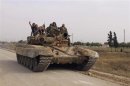 Forces of Syrian President Bashar al Assad are seen on a tank in Arjoun village near Qusair town