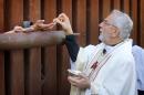 Most Reverend Gerald F. Kicanas, Bishop of Tucson, offers communion to people on the Mexican side of the international border, Tuesday, April 1, 2014, in Nogales, Ariz. Kicanas and Boston Archdiocese Cardinal Sean O'Malley, along with several Bishops who serve along the U.S./Mexico border, were visiting the border town to bring awareness to immigration reform and to remember those who have died trying to cross the border in years past. (AP Photo/Matt York)