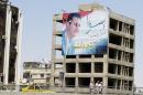 People walk past a huge billboard bearing a portrait of Syrian President Bashar al-Assad on July 15, 2014 in the capital Damascus