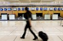 A passenger walks past vacant check in desks at Orly airport, west of Paris, France, during a strike by French air traffic controllers, Tuesday, June 11, 2013. Airlines have slashed flights in France as a strike by air traffic controllers fearful of a plan to unify European skies went into full force Tuesday. France's main airports have cut their flight timetables in half to cope with a three-day strike by air traffic controllers.(AP Photo/Jacques Brinon)