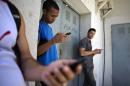In this April 1, 2014 file photo, students stand outside a building to find an Internet signal for their phones in Havana, Cuba. In programs revealed by the Associated Press in 2014, USAID secretly created a primitive social media program called ZunZuneo, staged a health workshop to recruit activists and infiltrated Cuba's hip-hop community. Those programs were part of a grassroots campaign aimed at undermining the Castro government through the citizenry, rather than directly targeting political leaders. (AP Photo/Ramon Espinosa, File)