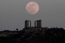 FILE - In this Saturday, May 5, 2012 file photo, a "supermoon" rises behind the Temple of Poseidon in Cape Sounion, Greece, southeast of Athens. The phenomenon occurs when the moon passes closer to Earth than usual. The event on Sunday, June 23, 2013 will make the moon appear 14 percent larger than normal, but the difference is so small that most skywatchers won’t notice. (AP Photo/Dimitri Messinis)