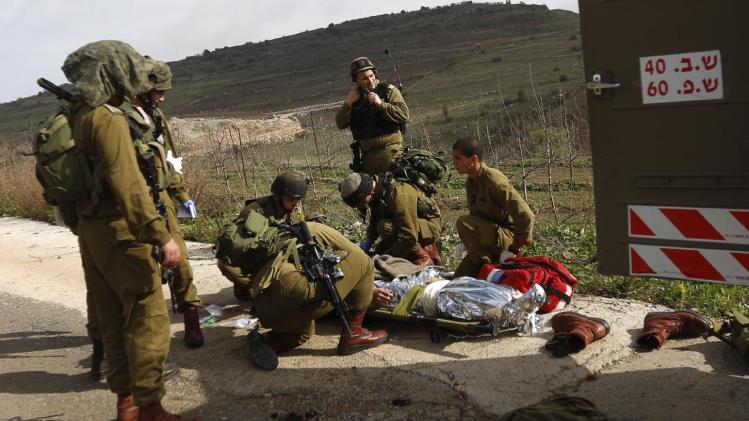 A wounded Israeli soldier is treated in the Golan Heights, Tuesday, March 18, 2014. A roadside bomb hit an Israeli patrol near the frontier with the Golan Heights on Tuesday, the army said, wounding four soldiers in the most serious violence to strike the area since the Syrian conflict began three years ago. Israel said it responded with artillery strikes on Syrian army targets. Israel captured the Golan Heights from Syria in the 1967 Middle East war and later annexed the strategic area in a move that was not internationally recognized. (AP Photo/Jinipix) ****ISRAEL OUT***