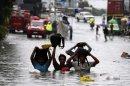 Un grupo de personas trata de no mojar sus pertenencias al cruzar una calle completamente inundada en Filipinas tras el paso del mismo tifón que azotó el sureste de China. EFE/Archivo