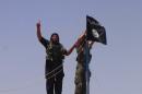 Islamic State group militants hang the Islamic Jihad flag on a pole at the top of an ancient military fort after they cut a road through the Syrian-Iraqi border between the Iraqi Nineveh province and the Syrian town of Al-Hasakah on June 11, 2014