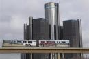 Two cars of the public rail are seen covered with a advertisement for 2014 Chevy Silverado pickup truck as they move past General Motors World Headquarters in Detroit