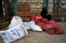 A woman sits next to sacks of humanitarian aid distributed by international aid agencies in Sanaa, on August 2, 2012