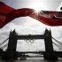 A flag on the back of a river boat flutters above Tower Bridge after the Olympic Rings were lowered into position for display in London