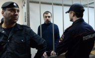 Mikhail Kosenko, an activist accused of violence at a rally on the eve of President Vladimir Putin's inauguration, stands in a defendant's cage in a court in Moscow on October 8, 2013