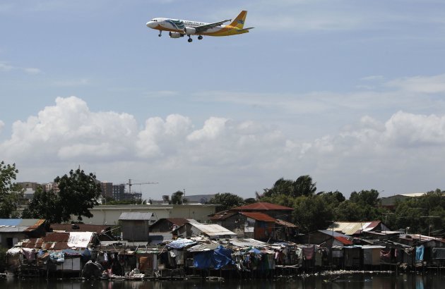 A Cebu Pacific Air (CEB) plane flies over a slum area in Manila April 10, 2012. Cebu Pacific Air will reroute its Manila-Osaka, Japan flights from April 12 to 16 as a precautionary measure against the planned North Korea's rocket launch. North Korea is scheduled to conduct a long-range ballistic missile test between April 12 and 16 despite protests from various countries including the Philippines, local media reported.    REUTERS/Romeo Ranoco (PHILIPPINES - Tags: POLITICS TRANSPORT)