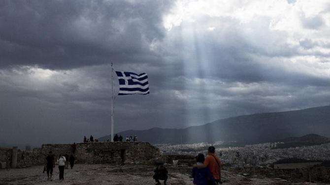 A Greek flag waves as the sunlight filters in through thick clouds on the Acropolis of Athens, in this photo dated Monday, June 22, 2015. The latest incarnation of Greece’s economic crisis over the span of a month saw Greece in the end accept harsh austerity measures from creditors to save the country from bankruptcy and possibly ignominiously getting kicked out of the eurozone. (AP Photo/Petros Giannakouris)