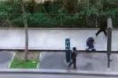 In this image made from amateur video recorded on Wednesday, Jan. 7, 2015 by Jordi Mir, masked gunman walk past a police officer moments after shooting him at blank range outside the offices of French satirical newspaper Charlie Hebdo in Paris. Paris residents captured chilling video images of two masked gunmen shooting a police officer after an attack at a French satirical newspaper. In the video, the gunmen armed with assault rifles are seen running up to an injured police officer, who lies squirming on the ground. The police officer raises his hands up before one of the assailants shoots him in the head at a close range. (AP Photo/Jordi Mir) NO SALES