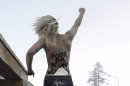 An activist of the Ukrainian feminist group FEMEN stands on a fence during a protest at the 43rd Annual Meeting of the World Economic Forum, WEF, in Davos, Switzerland, Saturday, Jan. 26, 2013. (AP Photo/Keystone/Jean-Christophe Bott)