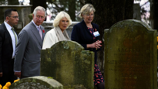 Prince Charles of Wales (2-L) and his wife Camilla (C), Duchess of Cornwall, listen to their translator during a tour of the British cemetery at the Real del Monte community in Hidalgo State on November 2, 2014