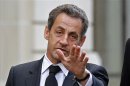 Former French President Nicolas Sarkozy reacts as he leaves his car in Paris