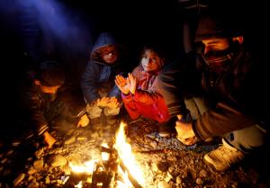 Migrants and refugees try to warm themselves by a fire&nbsp;&hellip;