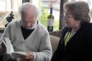 In this photo released by Chile's Presidential Press Office, Chilean poet poet Nicanor Parra, left, sits with Chile's President Michelle Bachelet at his home, one day before his 100th birthday, in Las Cruces, Chile, Thursday, Sept. 4, 2014. In 2011, Parra won the Spanish-speaking world's highest literary honor, the Cervantes Prize, for his influential work mixing everyday slang with traditional verse. (AP Photo/Chile Presidential Press Office)
