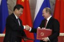 Russia's President Vladimir Putin exchanges documents with his Chinese counterpart Xi Jinping during a signing ceremony at the Kremlin in Moscow