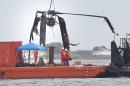 Crews lower a piece of a Black Hawk helicopter onto a barge in the Santa Rosa Sound near Pritchard Point, Friday, March 13, 2015, in Navarre, Fla. The helicopter, which crashed in dense fog during a training mission, was carrying seven Marines based in North Carolina along with four National Guard soldiers from Louisiana. All were killed. (AP Photo/Northwest Florida Daily News, Nick Tomecek)