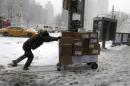 A UPS delivery man struggles to push a cart through Columbus Circle as snow falls in New York