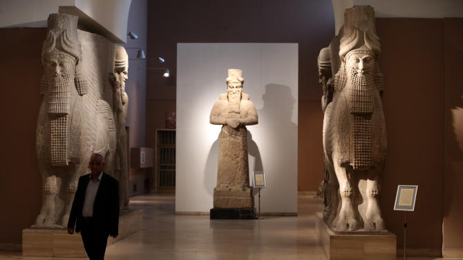 FILE - In this March 1, 2015. file  photo, a man at Iraq&#39;s National Museum in Baghdad walks past two ancient Assyrian human-headed winged bull statues. Islamic State militants &quot;bulldozed&quot; the renowned archaeological site of the ancient city of Nimrud in northern Iraq on Thursday, March 5, 2015, using heavy military vehicles, the government said. Nimrud was the second capital of Assyria, an ancient kingdom that began in about 900 B.C., partially in present-day Iraq, and became a great regional power. The city, which was destroyed in 612 B.C., is located on the Tigris River just south of Iraq&#39;s second largest city, Mosul, which was captured by the Islamic State group in June(AP Photo/Karim Kadim, File)