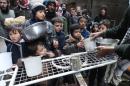Residents of Syria's besieged Yarmuk Palestinian refugee camp, south of Damascus, gather to collect food aid at the adjacent Jazira neighborhood on February 13, 2015