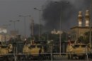 Army vehicles are seen as smoke rises in the background during clashes between security forces and supporters of ousted Egyptian President Mursi at Rabba el Adwia Square, where the protesters are camping, in Cairo