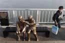 A man walks past a statue of a person comforting another on the Mapo Bridge in central Seoul
