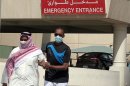 A man, wearing a surgical mask as a precautionary measure against the novel coronavirus, helps a friend who has the common flu near a hospital in Khobar city in Dammam