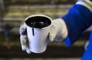 A worker holds a cup of heavy oil before it is shipped to the market at the Cenovus Energy Christina Lake SAGD project south of Fort McMurray