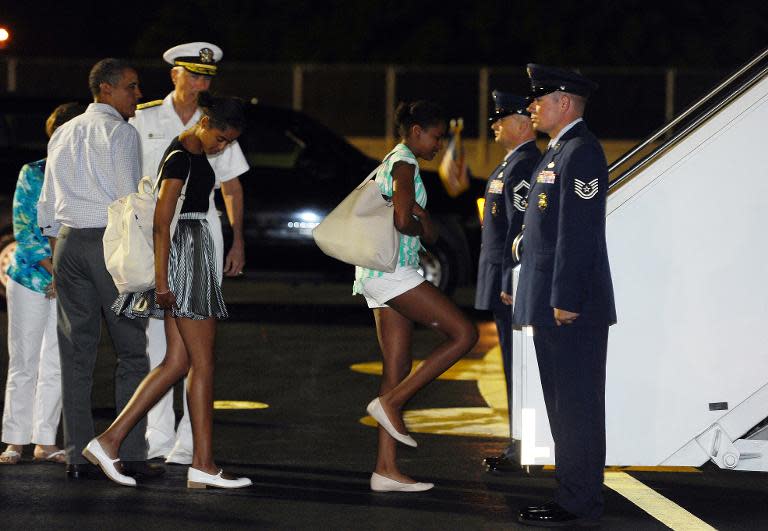Barack Obama (left) looks on as daughters Malia (centre) and Sasha board Air Force One at Hickam Air Force Base in Honolulu, Hawaii, on January 4, 2014 to return to Washington DC