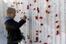 A young visitor takes photographs of names of the soldiers decorated with flowers at the Lone Pine Australian memorial in Gallipoli
