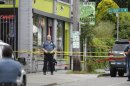 A Seattle Police officer stands outside a cafe where a shooting took place, Wednesday, May 30, 2012. A gunman opened fire at the cafe in Seattle's University district Wednesday, killing two people and critically wounding three others. Police are searching for the gunman, described as a man in his 30s wearing dark clothes. (AP Photo/Ted S. Warren)