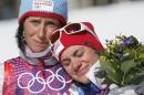 Norway's gold medal winner Marit Bjoergen, left, hugs bronze medal winner Heidi Weng during the flower ceremony of the women's cross-country 15k skiathlon at the 2014 Winter Olympics, Saturday, Feb. 8, 2014, in Krasnaya Polyana, Russia. (AP Photo/Dmitry Lovetsky)