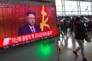People walk past a television news broadcast at a railway station in Seoul on January 1, 2017 showing North Korean leader Kim Jong-Un's New Year's speech