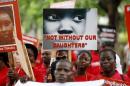 Bring Back Our Girls (BBOG) campaigners hold banners as they walk during a protest procession marking the 500th day since the abduction of girls in Chibok, along a road in Lagos