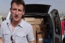 FILE - This undated file photo provided by the Kassig Family shows Peter Kassig standing in front of a truck filled with supplies for Syrian refugees. A new graphic video purportedly produced by Islamic State militants in Syria released Sunday Nov. 16, 2014 claims U.S. aid worker Kassig was beheaded. (AP Photo/Courtesy Kassig Family, File)