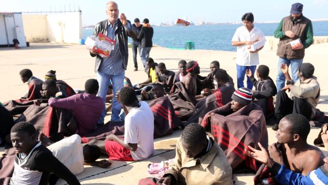 Migrants, who were rescued by the Libyan coastguard in the Mediterranean Sea off the coast, receive food and blankets on December 21, 2015