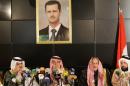 Sheikh Mohammed Faris (2nd from L), a member of the Tay tribe, sits under a portrait of Syrian President Bashar al-Assad as he chairs a press conference of Syria's leading pro-government tribes in Damascus on June 19, 2015