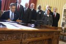 U.S. President Barack Obama signs H.R. 6156 at desk in the Oval Office of the White House in Washington