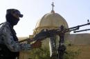 A masked policeman mans a machinegun atop an armoured vehicle to secure a Christian church in Mosul