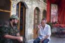 Michael Oberi, a Christian, talks with a Syrian rebel at Mar Elias House in Aleppo on September 16, 2013