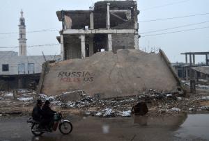 Syrians ride a motorbike past a collapsed building&nbsp;&hellip;